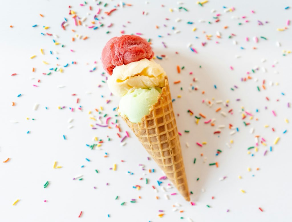 A waffle cone with strawberry, pineapple, and lime ice cream.